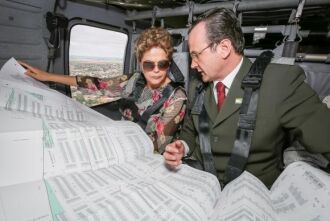 Durante o sobrevoo, a presidenta Dilma Rousseff e o prefeito de Uruguaiana, Luiz Augusto Schneider, examinam um  levantamento  de  locais  atingidos  pelas  enchentes